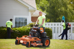 Team of BruZiv lawn maintenance experts working together to clean up a residential yard