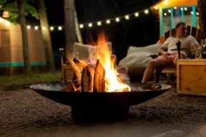 Backyard feature lighting and stone fire pit area and man relaxing by the fire