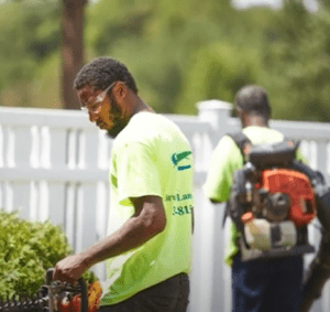 Two men blowing grass in yard