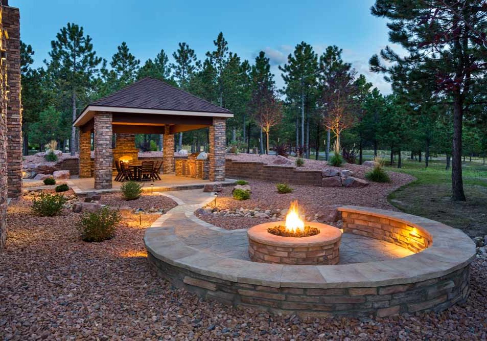 Residential landscape featuring firepit, fireplace, and stone pavilion