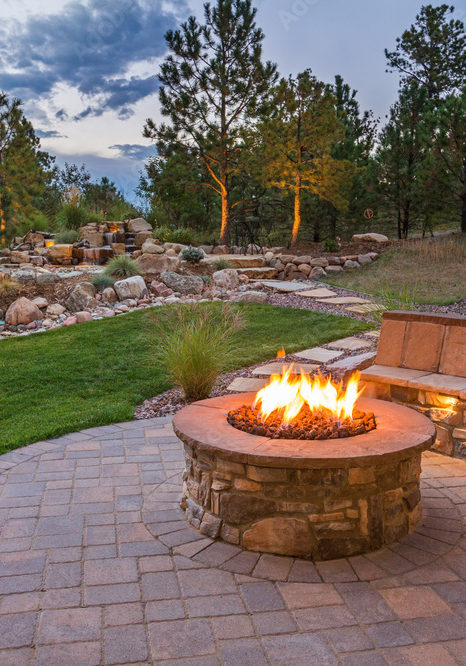 Outdoor stone fire pit with semicircular stone seating in grassy area