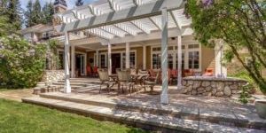 Lovely outdoor deck patio space with white dining pergola in the backyard of a luxury house.